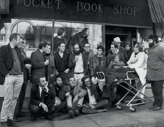 A group of people in three rows in front of a bookstore. 