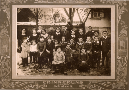 A group of children sitting and standing with a teacher standing behind them