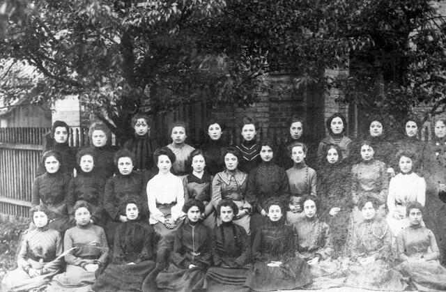 Three rows of women in formal dresses