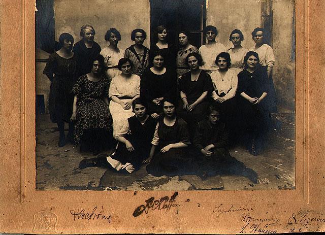 A group of women and girls, standing and seated, outside a building