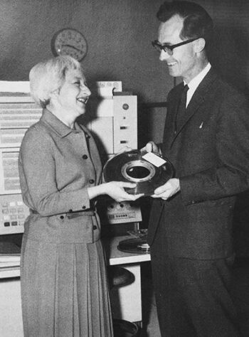 Henriette Avram, on left, presents a magnetic tape to Richard Coward, right