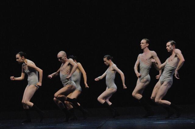 Six dancers onstage in thin grey leotards and long black socks