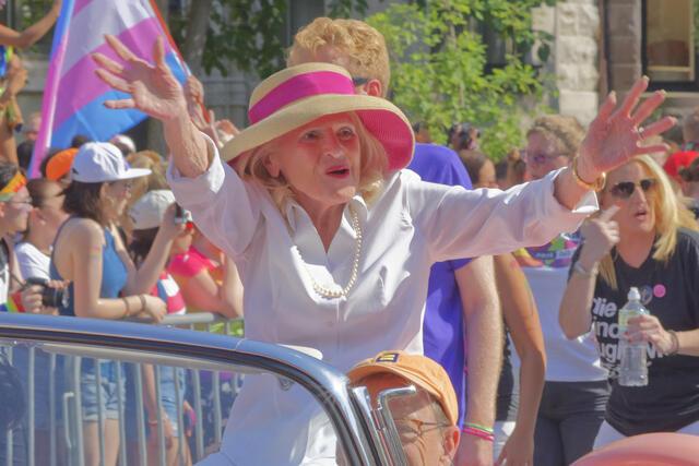 Edie Windsor wearing a hat with a pink ribbon waving to crowds at DC Pride 2017