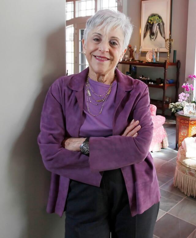Lynn Schusterman leaning against a wall in front of a sitting room