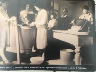 Aurelia Josz standing before a large tank with her female students, some of whom are holding honey frames.