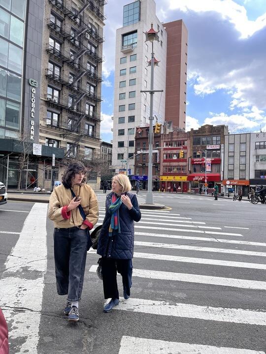 Two women talk while crossing the street