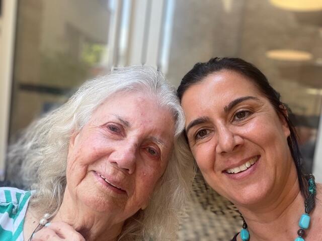 Faces of two women, mother and daughter, one with white, wavy hair and one with dark hair worn up