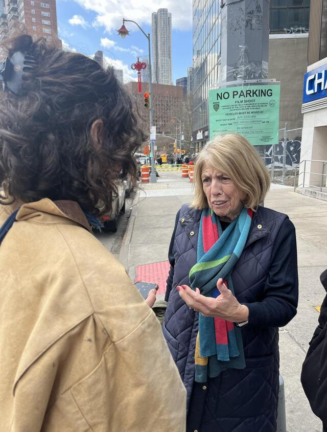 One woman with her back to camera holds out a recorder to interview an older woman