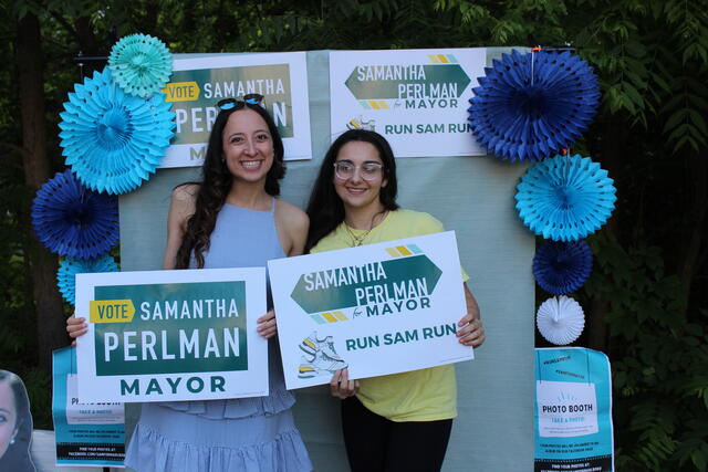 Two people holding signs that read "Vote Samantha Perlman"
